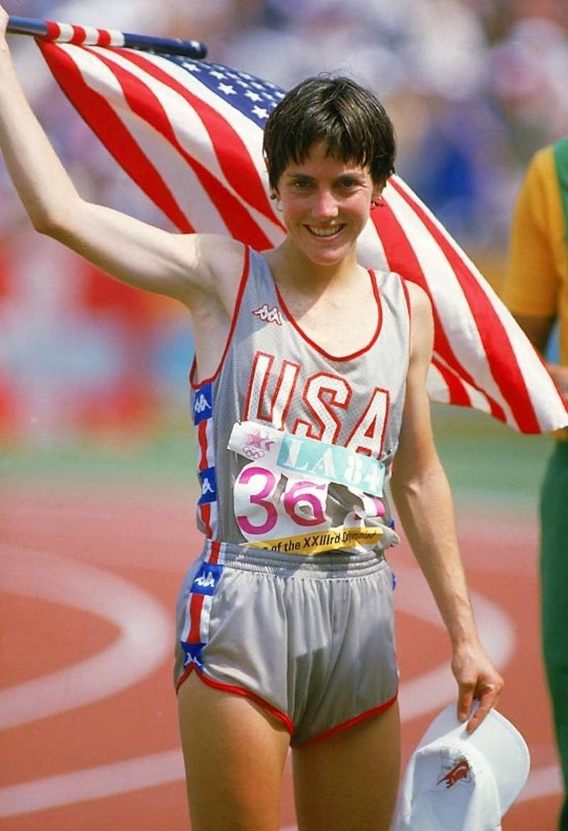 Joan Benoit holding an American flag and a cap after the 1984 Olympic marathon