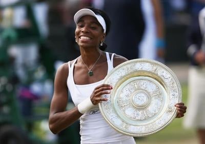 Venus Williams smiling and holding the Wimbledon trophy