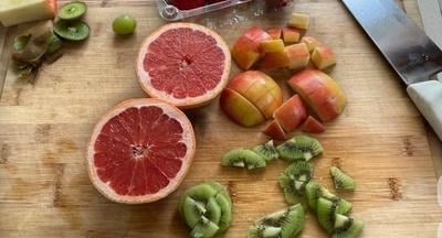 A cut grapefruit and other fruit on a board