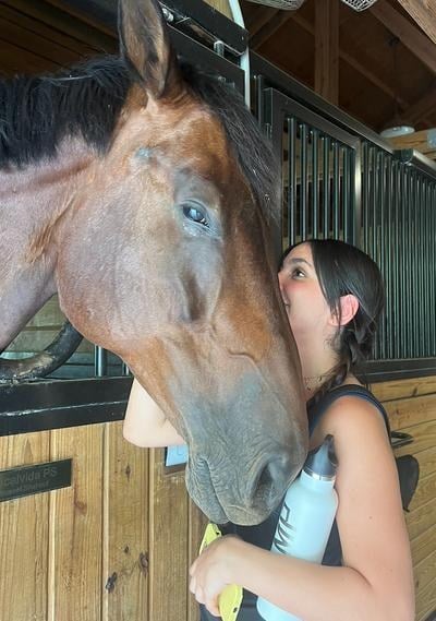 A woman hugging a horse in a barn